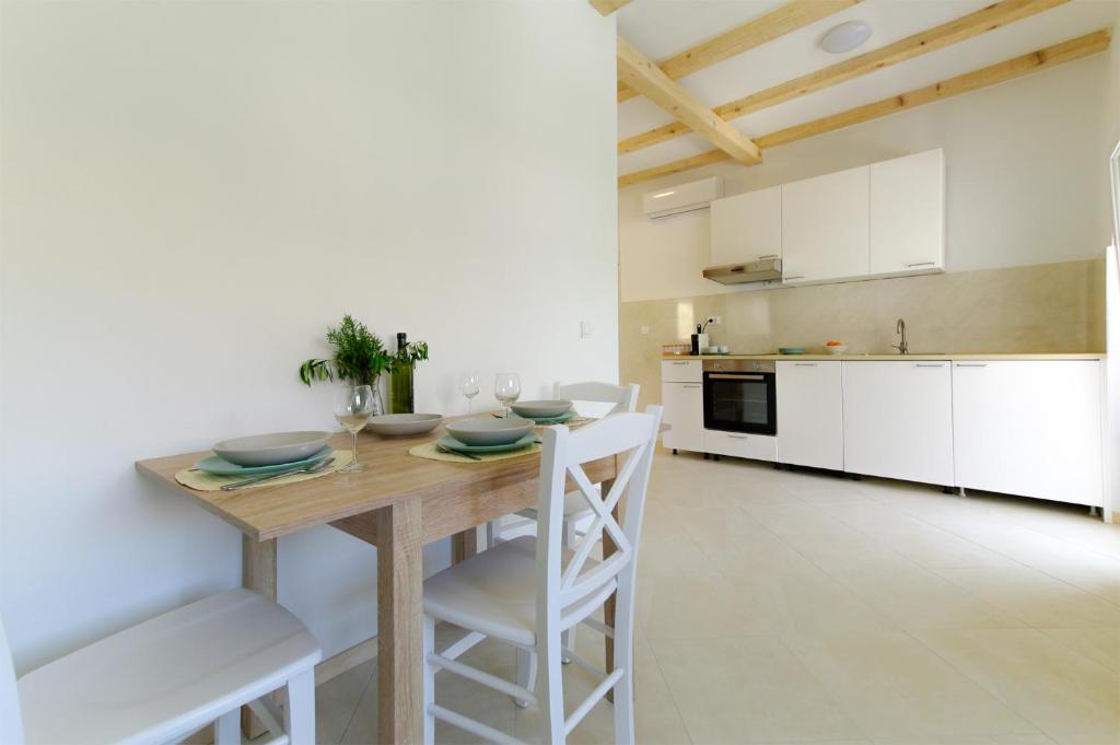 eine Küche mit einem Holztisch und weißen Schränken in der Unterkunft Apartmani Porat Sali in Sali
