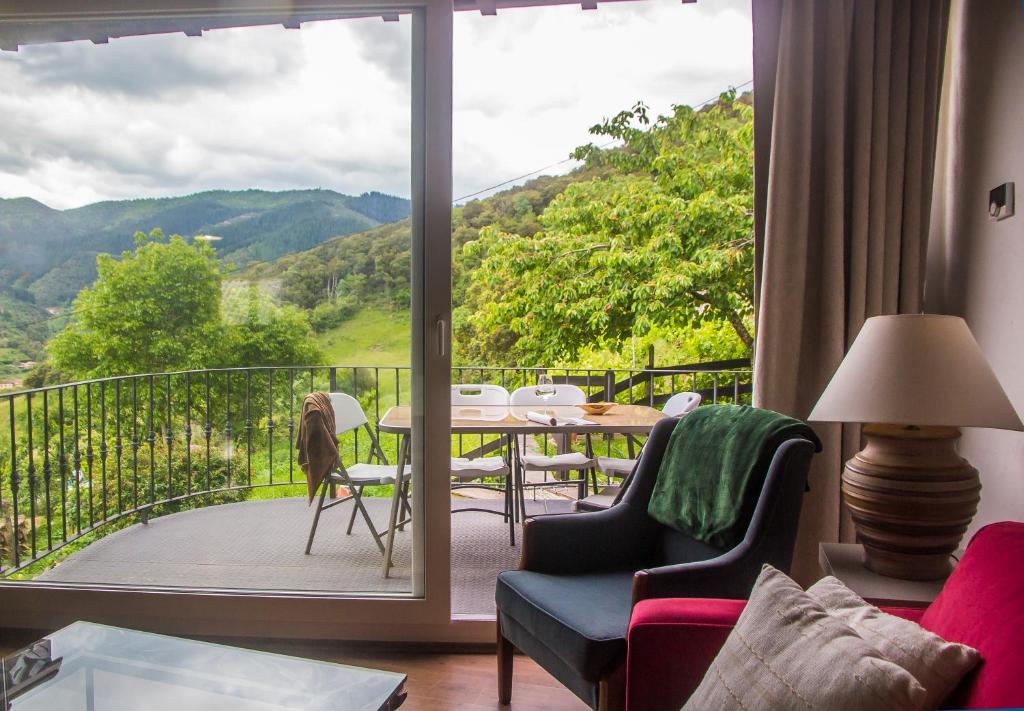 sala de estar con balcón con mesa y sillas en Armaño Rural en Tama