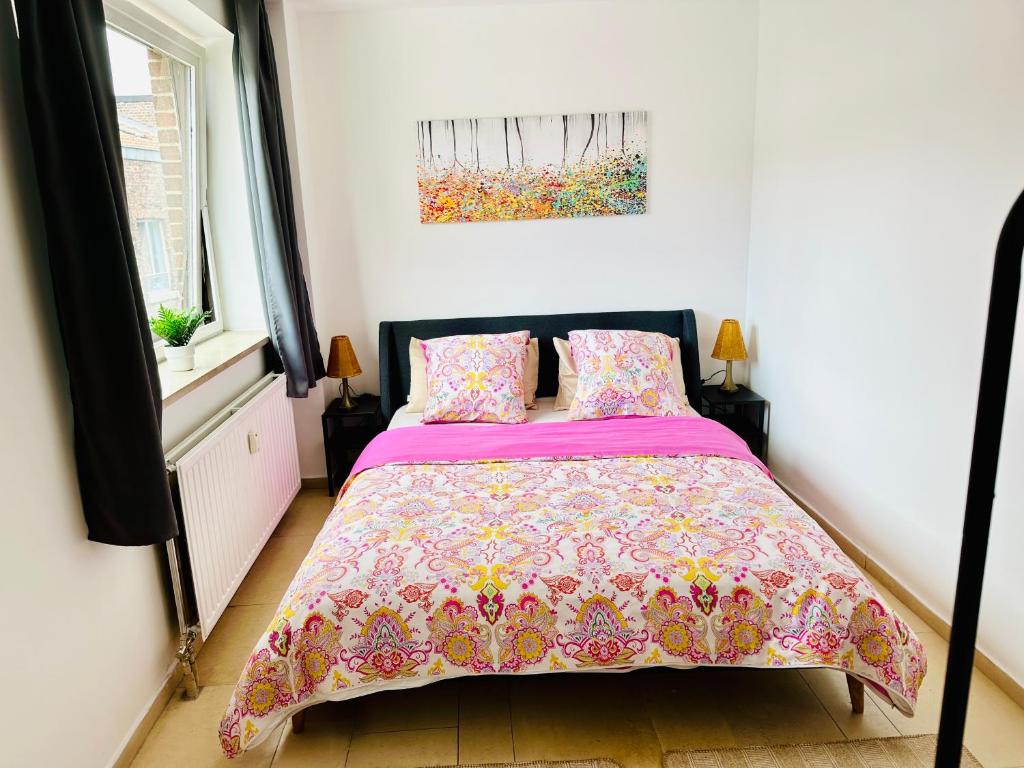 um quarto com uma cama com uma colcha rosa em Urban Sejour - Hyper Center em Liège