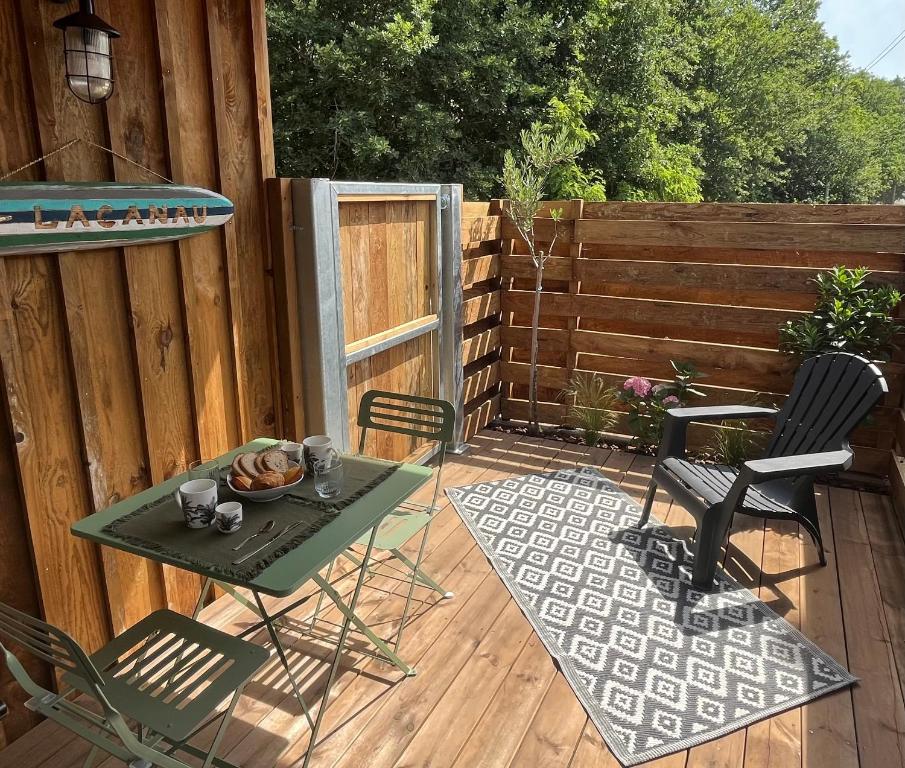 un patio con mesa y sillas en una terraza en Le p'tit canaulais - Logement entier - rez de jardin - paisible, en Lacanau