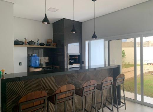 a kitchen with a bar with chairs around it at Casa aconchegante in Sinop
