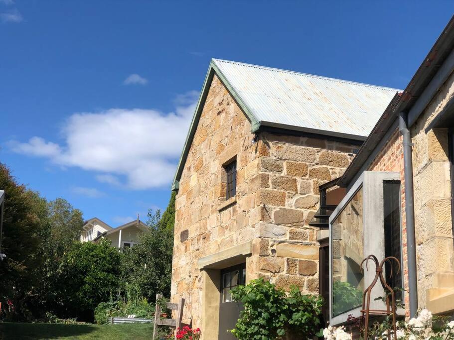 an old stone building with a roof at Macquarie Street Stable in Hobart