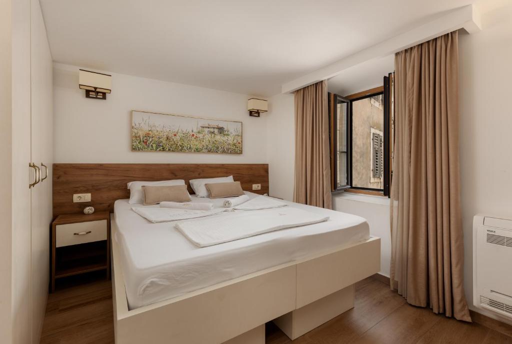 een slaapkamer met een groot wit bed en een raam bij Apartment Amigo Old Town Kotor in Kotor