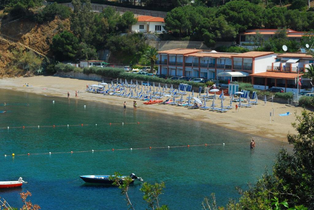 a beach with chairs and a boat in the water at Hotel Stella Maris in Capoliveri