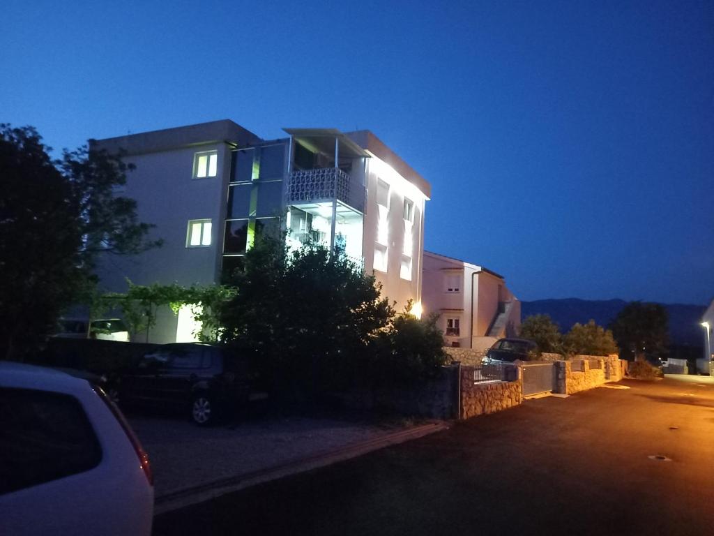 un bâtiment avec une voiture garée devant lui dans l'établissement D,apartman, à Omišalj