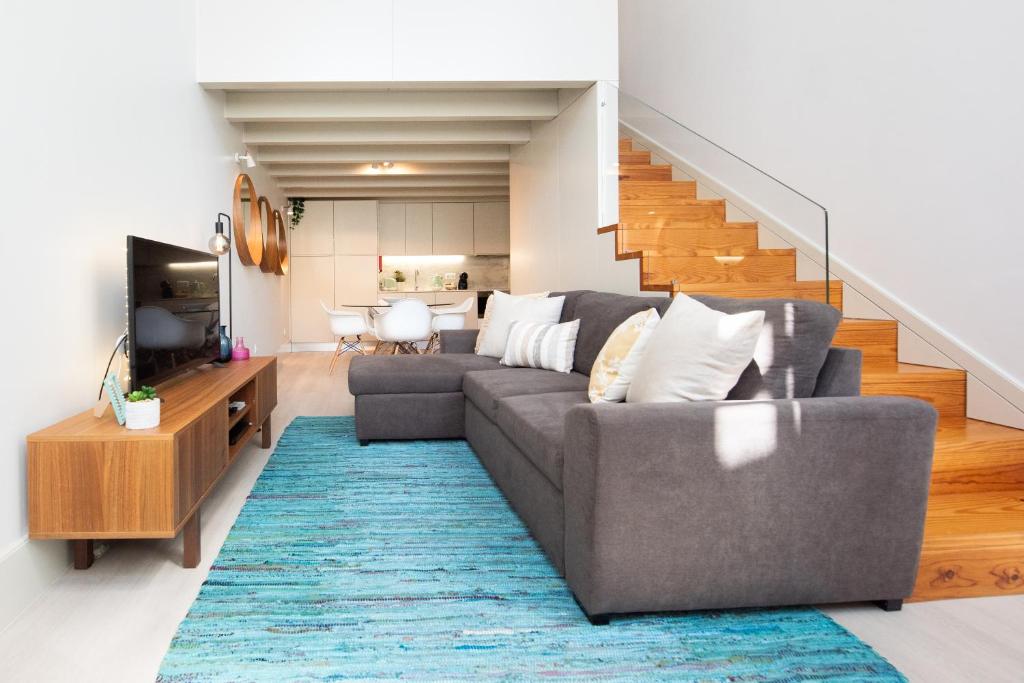 a living room with a couch and a television and stairs at Casa Barros - Miragaia in Porto