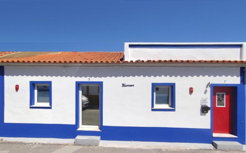 Bluemoon Campinho (Alqueva) في Campinho: مبنى باللون الأزرق والأبيض مع باب احمر