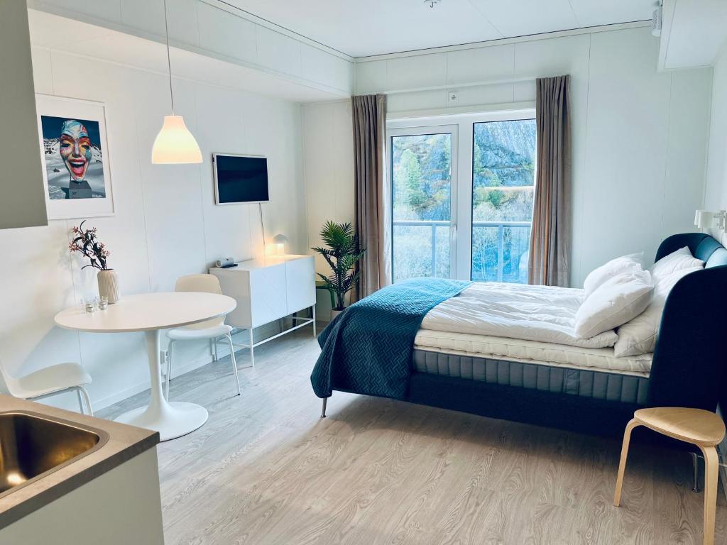 a bedroom with a bed and a table and a window at Lofoten Studio Penthouse in Svolvær