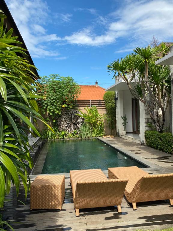 a backyard with a swimming pool and two chairs and a house at Villa Krishna in Canggu
