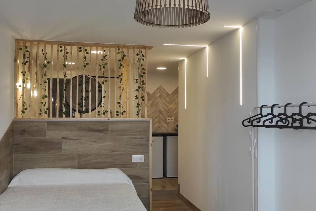 a bedroom with a bed with a wooden headboard at Estudio con balcón a 9min. del centro en metro in Seville