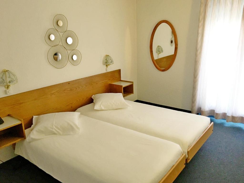 a bedroom with two beds and a mirror at Hôtel de la Plage à Gland in Gland