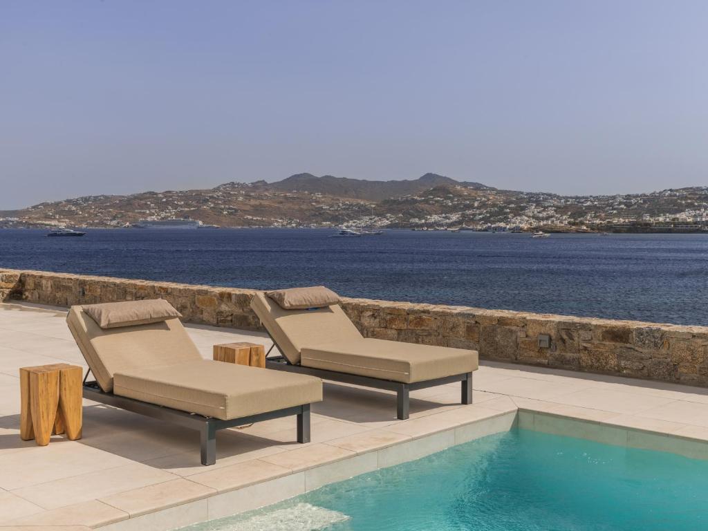 dwa leżaki i basen przy wodzie w obiekcie Star villa by Bestofmikonos w mieście Mykonos