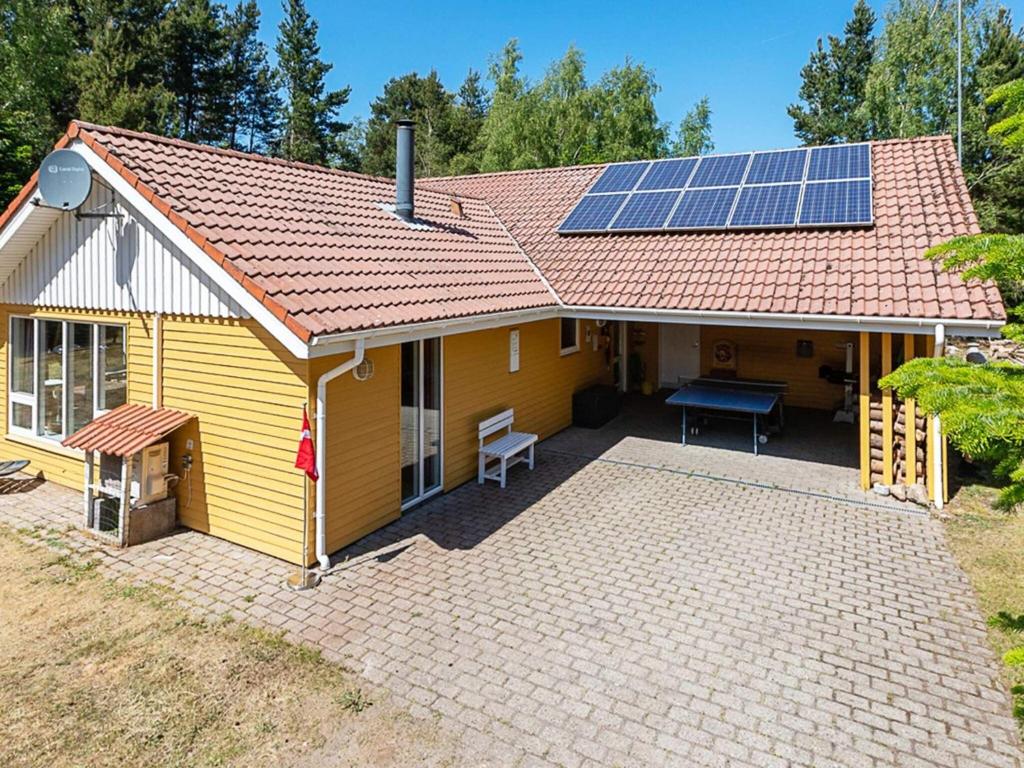 una casa amarilla con paneles solares en el techo en 10 person holiday home in H jslev, en Bøstrup