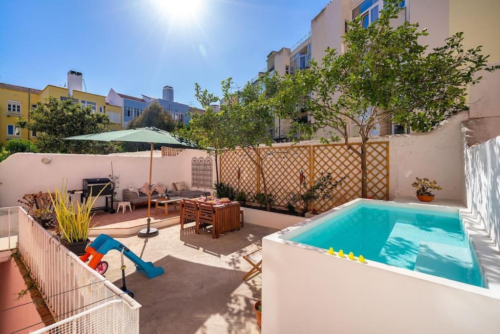 a backyard with a swimming pool and a patio with a table at Flat Art - Luxury with private Pool & Garden in Lisbon