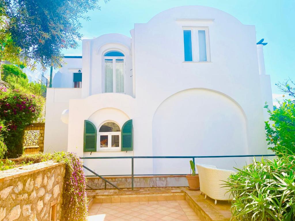 a white house with green shutters at Villa La Zagara by CapriRooms in Capri