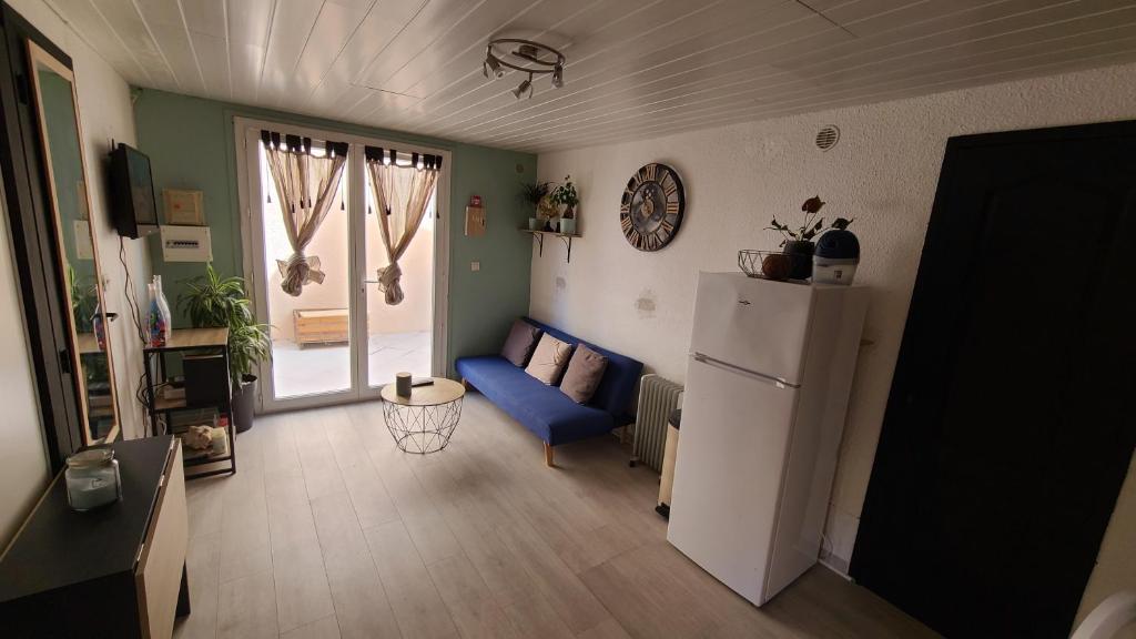 a living room with a blue couch and a refrigerator at Appartement en résidence avec parking in Le Barcarès