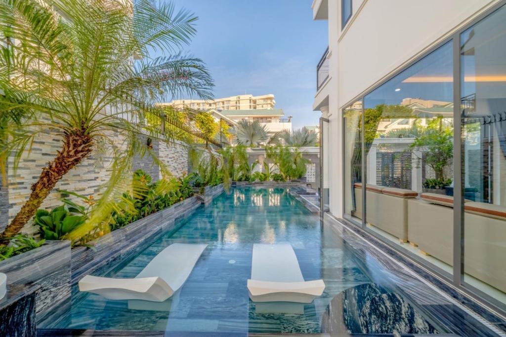 une piscine avec des chaises et des palmiers sur un immeuble dans l'établissement B2-21 Hoàng My Villages, à Vung Tau