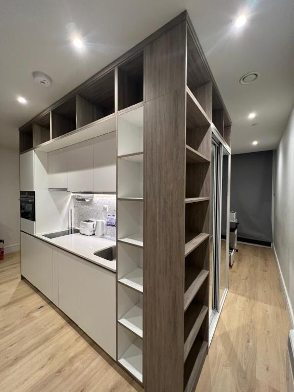 a kitchen with white and brown cabinets and shelves at LHR Apartments in London