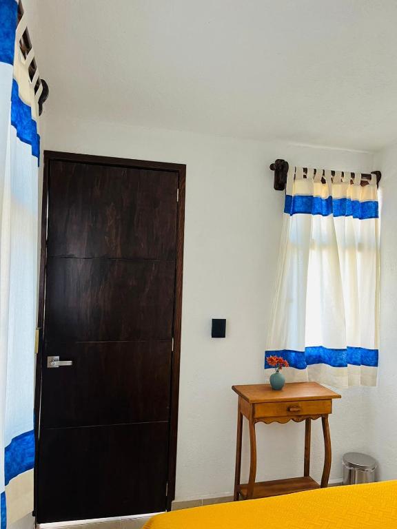 a bedroom with a door and a table next to a bed at Hostal Gautamas Guest rooms, hostal para viajeros,backpackers hostel in Tepoztlán