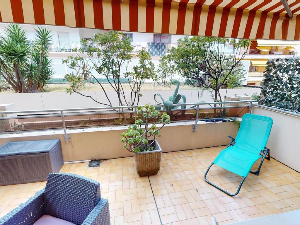 un patio avec deux chaises et une chaise bleue sur un balcon dans l'établissement Studio climatisé avec terrasse au calme, centre de Menton, proche plages et commerces - FR-1-196-335, à Menton