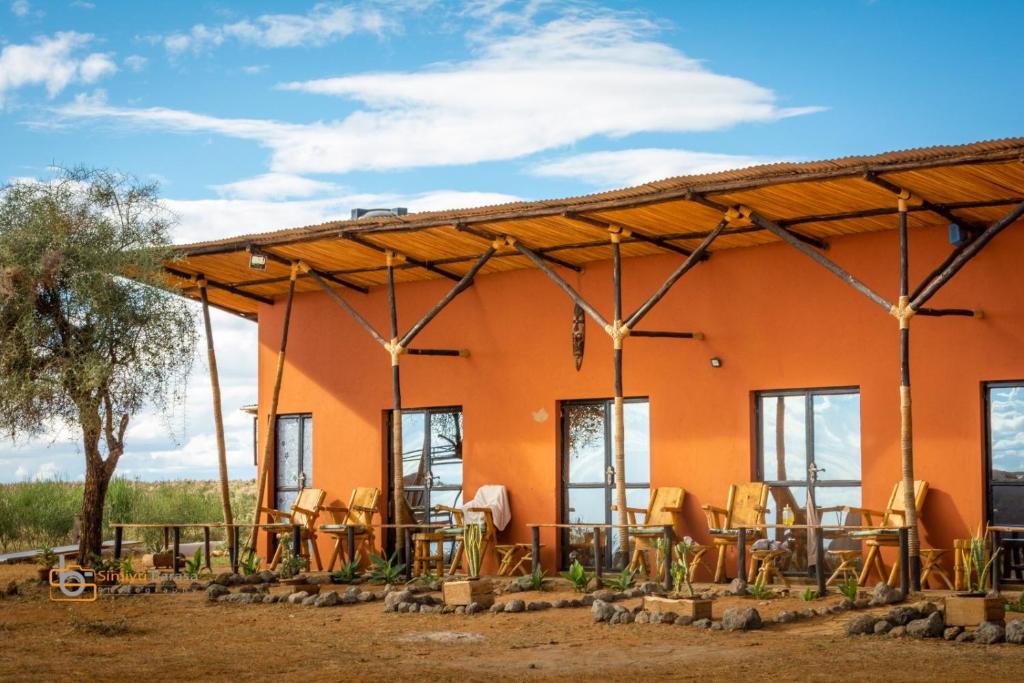 ein Haus mit Tischen und Stühlen davor in der Unterkunft The Red House in Amboseli-Nationalpark