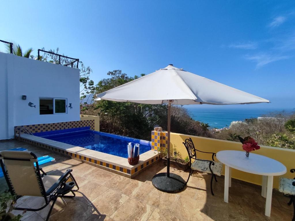 een villa met een zwembad en een parasol bij Casa las Palmas in Manzanillo