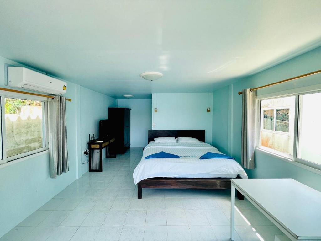 a blue bedroom with a bed and two windows at Naiharn On The Rock Resort Phuket in Nai Harn Beach