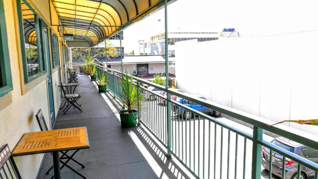 a balcony with benches and tables on a building at Stay Hostel Rotorua in Rotorua