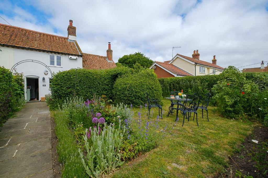 a garden with a table and chairs and flowers at 5 Mariners View in Friston