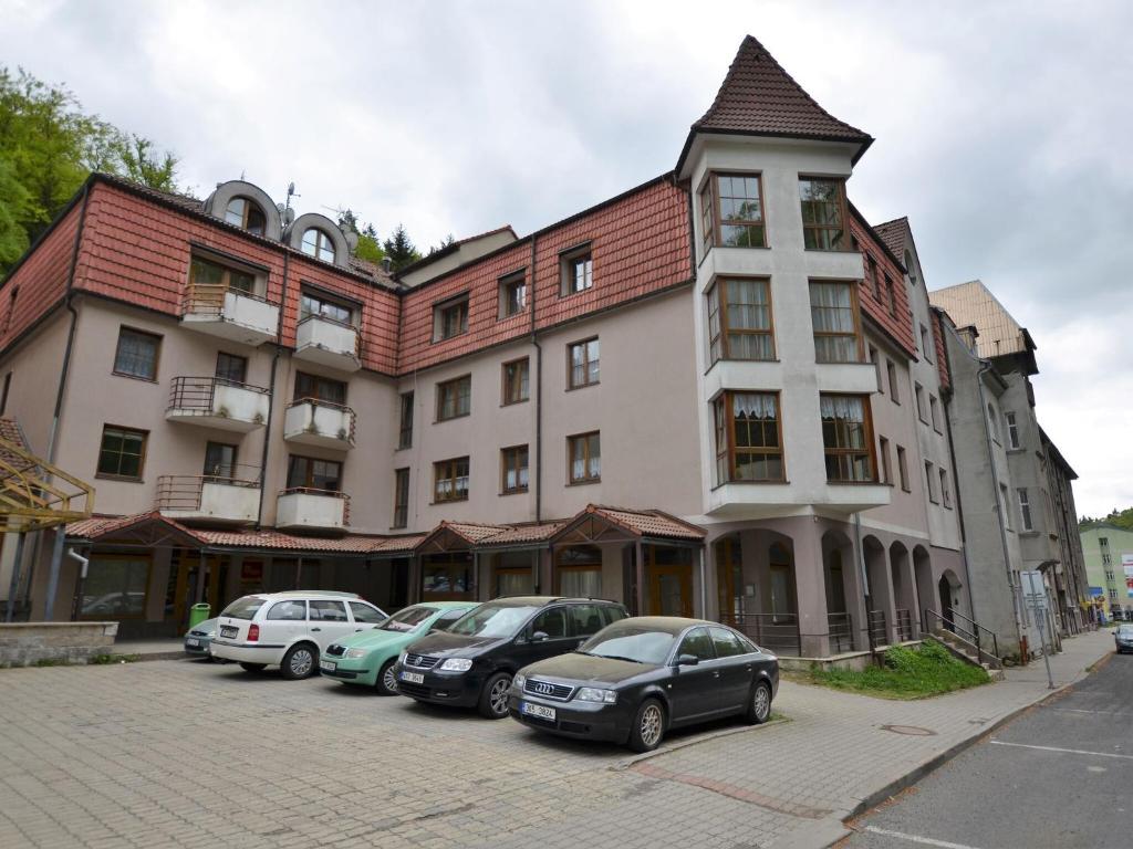 un grand bâtiment avec des voitures garées devant lui dans l'établissement Snug Apartment in Jachymov near Ski area, à Jáchymov