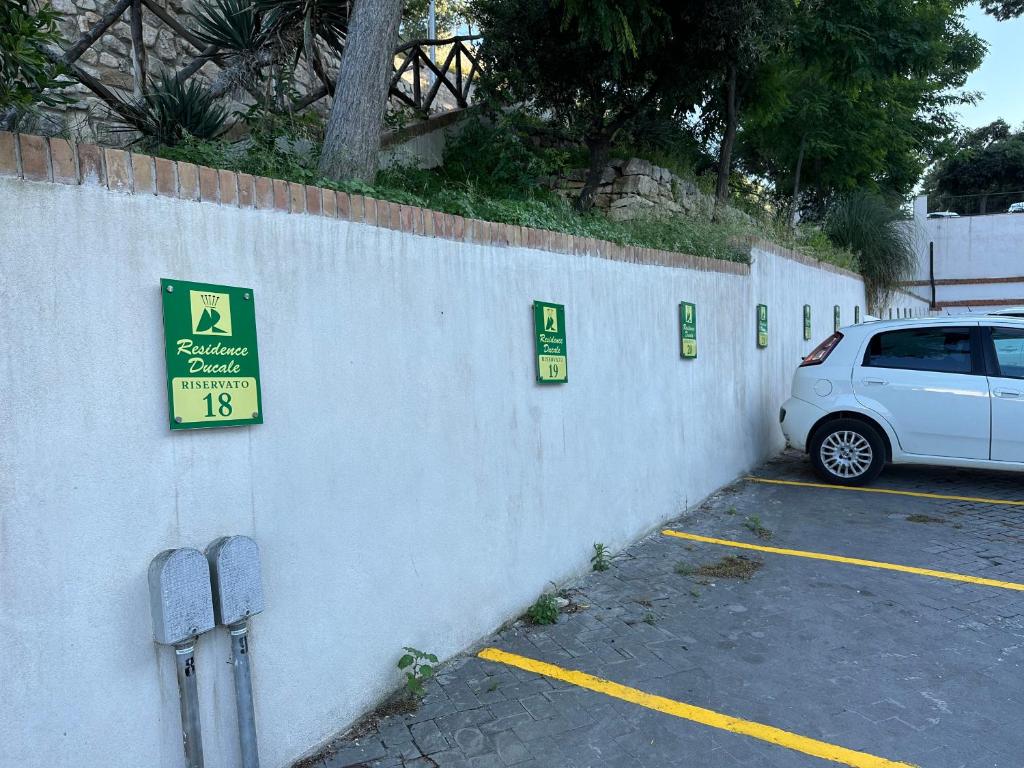 a white car parked in a parking lot next to a wall at Residence Ducale in Rodi Garganico