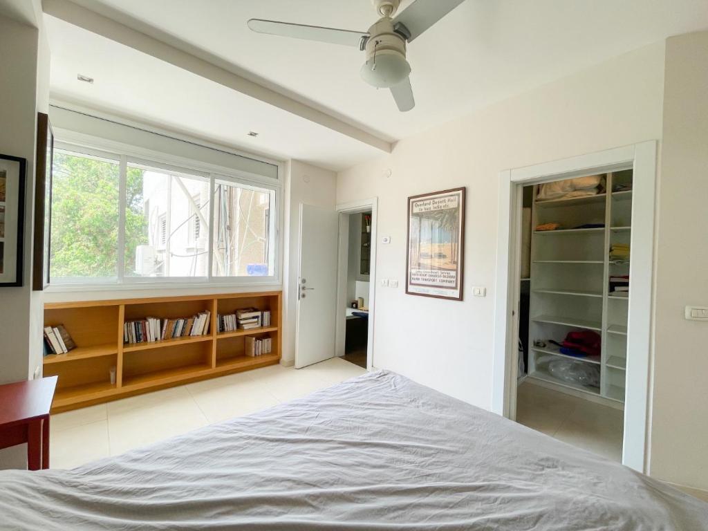 a white bedroom with a bed and a window at Spacious cosy & renovated flat in central Tel Aviv in Tel Aviv