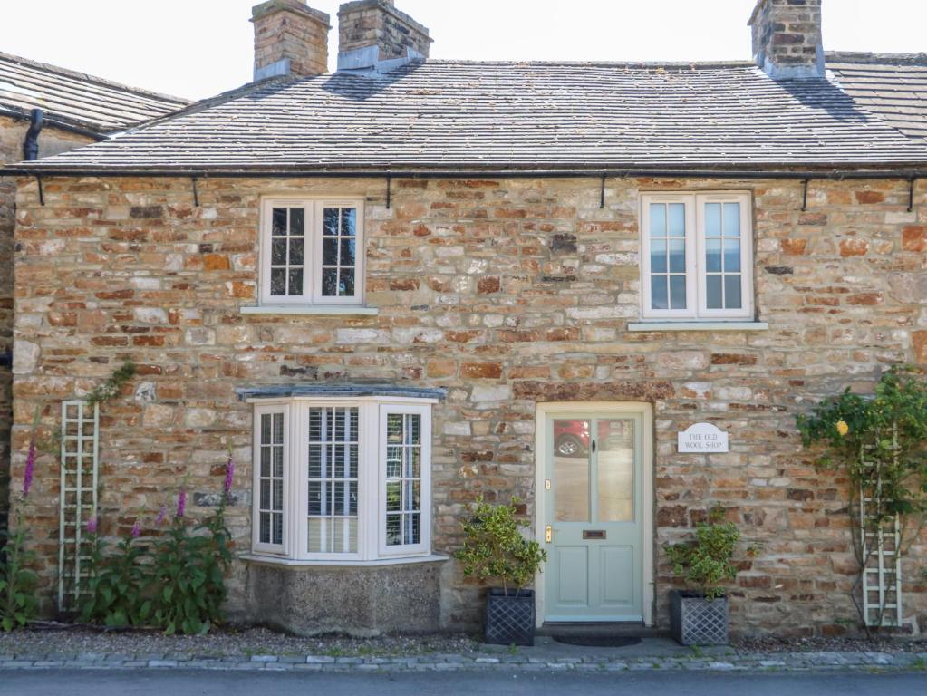 a brick house with a blue door at Old Wool Shop in Leyburn