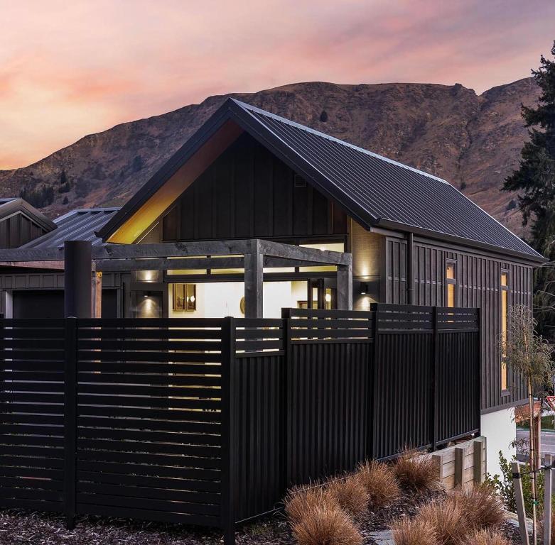 a house with a black fence in front of it at Little Alp Chalet in Queenstown