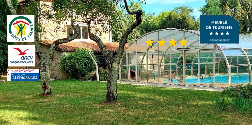 a building with a swimming pool and signs in the grass at Gîte La Buissière Duravel piscine couverte privative in Duravel