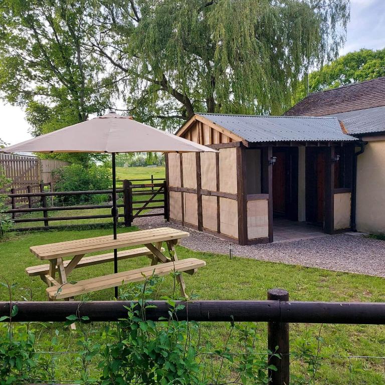 a picnic table with an umbrella next to a building at Spacious self catering accommodation near HayOnWye in Hay-on-Wye