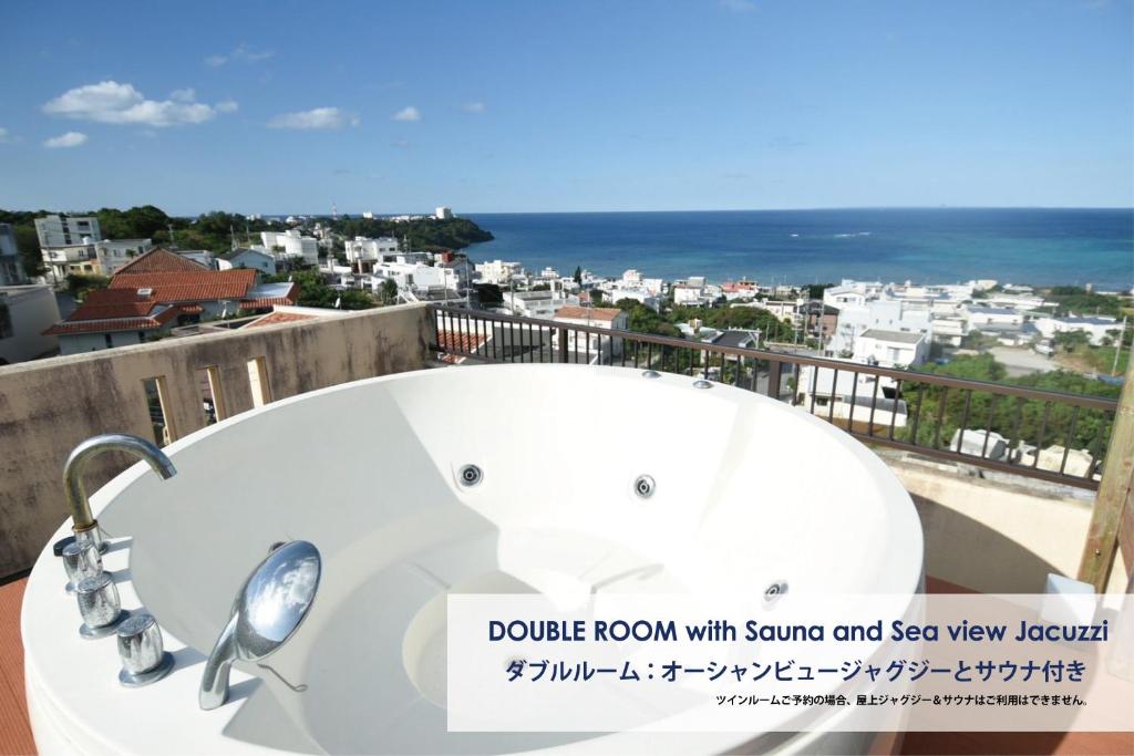 a bath tub on a balcony with a view of the ocean at FIRST STREET Okinawa Yomitan-son Oceans -SEVEN Hotels and Resorts- in Yomitan