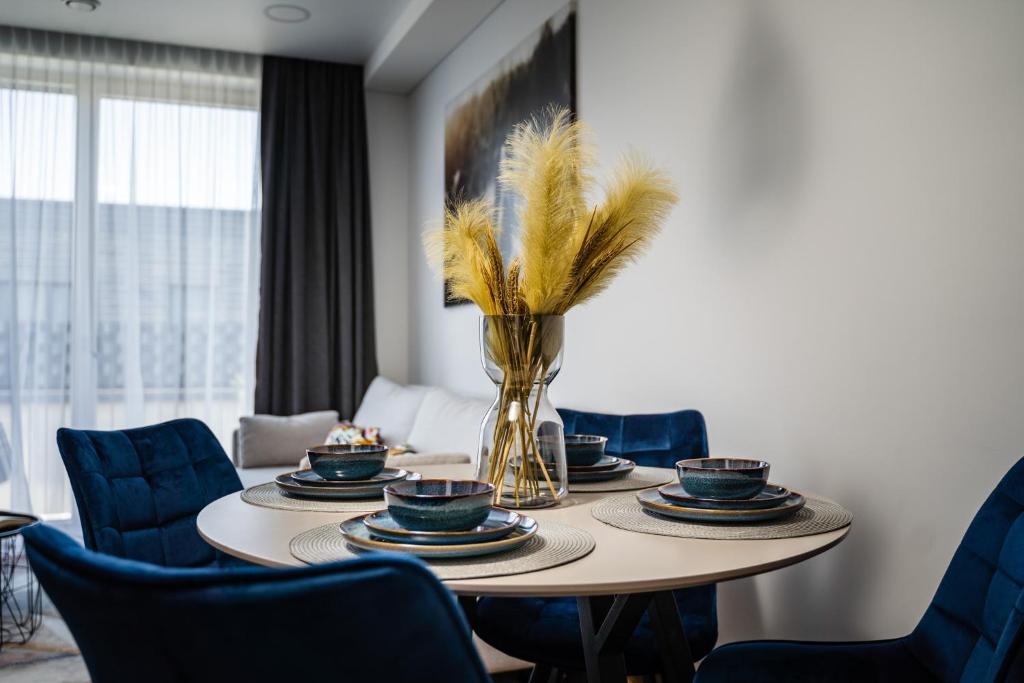 a dining room table with blue chairs and a vase with feathers at Lazdyneliu Vingis in Vilnius