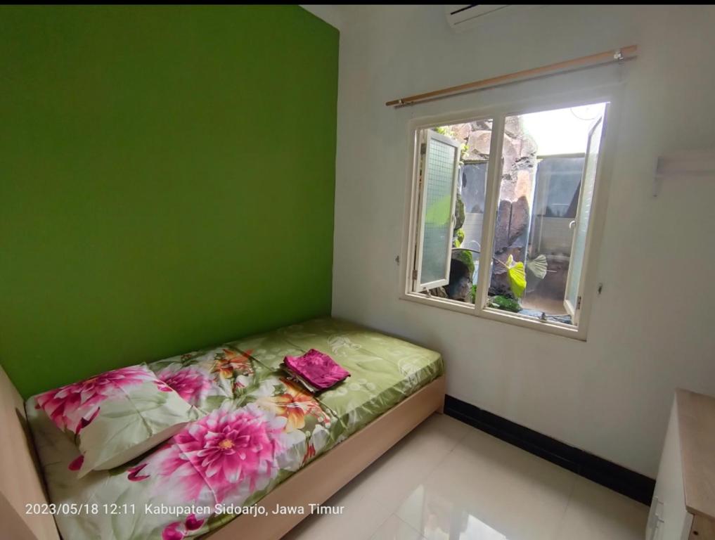 a green room with a bed and a window at Sidoarjo Homestay 