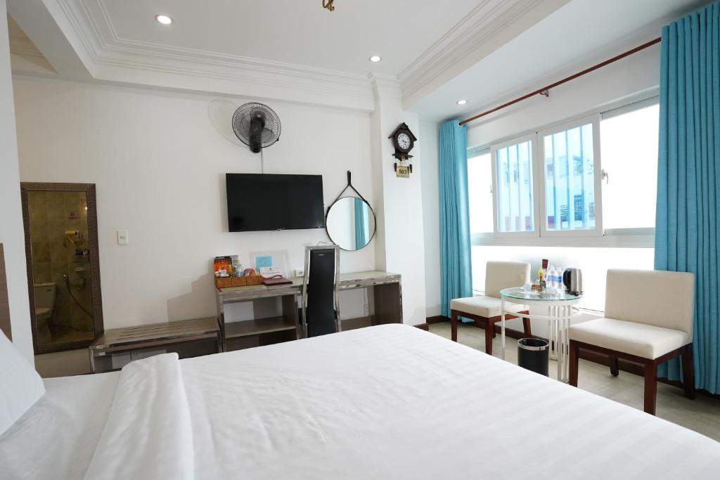 Schlafzimmer mit einem Bett, einem Schreibtisch und einem TV in der Unterkunft A25 Hotel - 14 Phó Đức Chính in Ho-Chi-Minh-Stadt