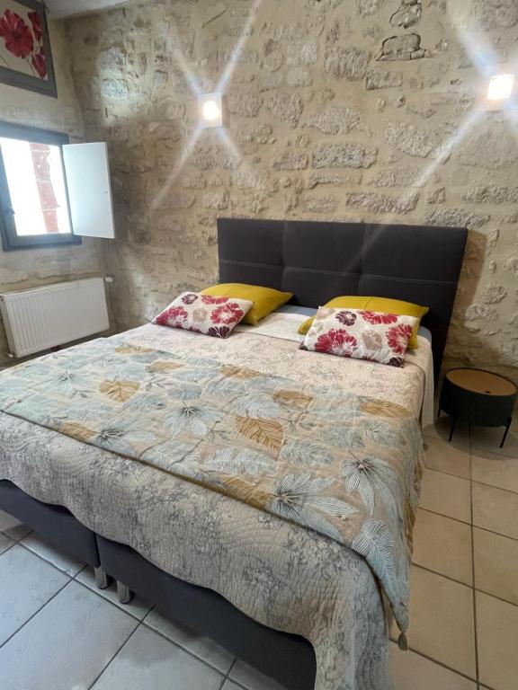 um quarto com uma cama grande e uma parede de pedra em Le Cherche Midi - Appartement centre historique d'Uzès em Uzès