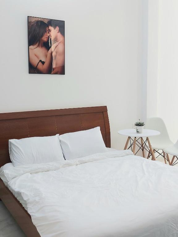 ein Schlafzimmer mit einem weißen Bett mit einem Bild an der Wand in der Unterkunft Min homestay 5 in Buôn Ðũng