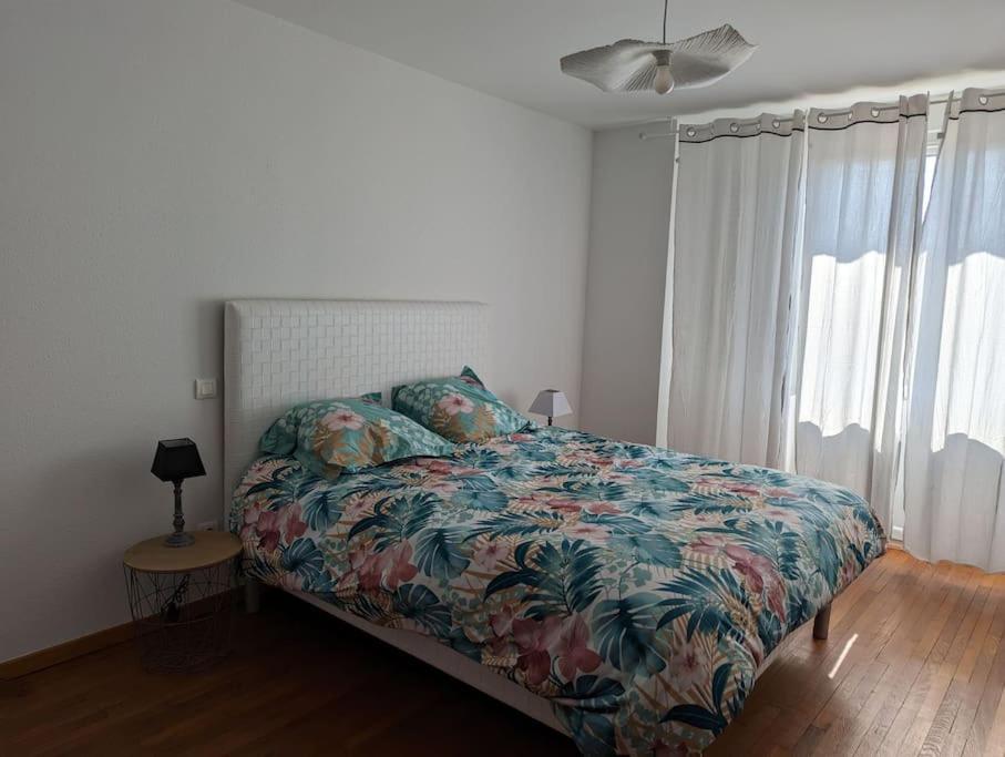um quarto com uma cama com um edredão colorido em appartement plein centre Saint die des Vosges em Saint-Dié-des-Vosges