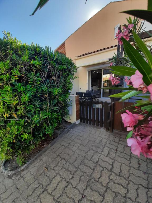 una pasarela que conduce a un edificio con arbustos y flores en Plage de la Roquille, en Cap d'Agde
