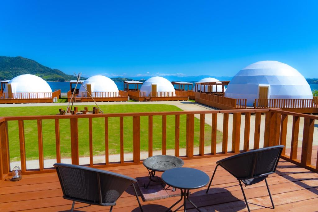 a deck with chairs and tables and white domes at GLAMPDOME SETOUCHI-SHIMANAMI in Onomichi
