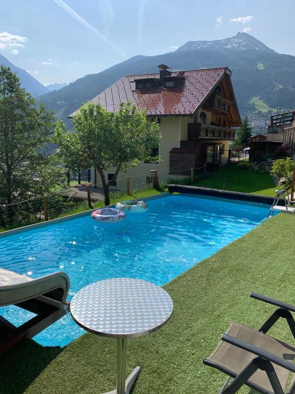 a pool with a table and chairs and a house at Appartementhaus Gastein / Haus Sammie in Bad Gastein