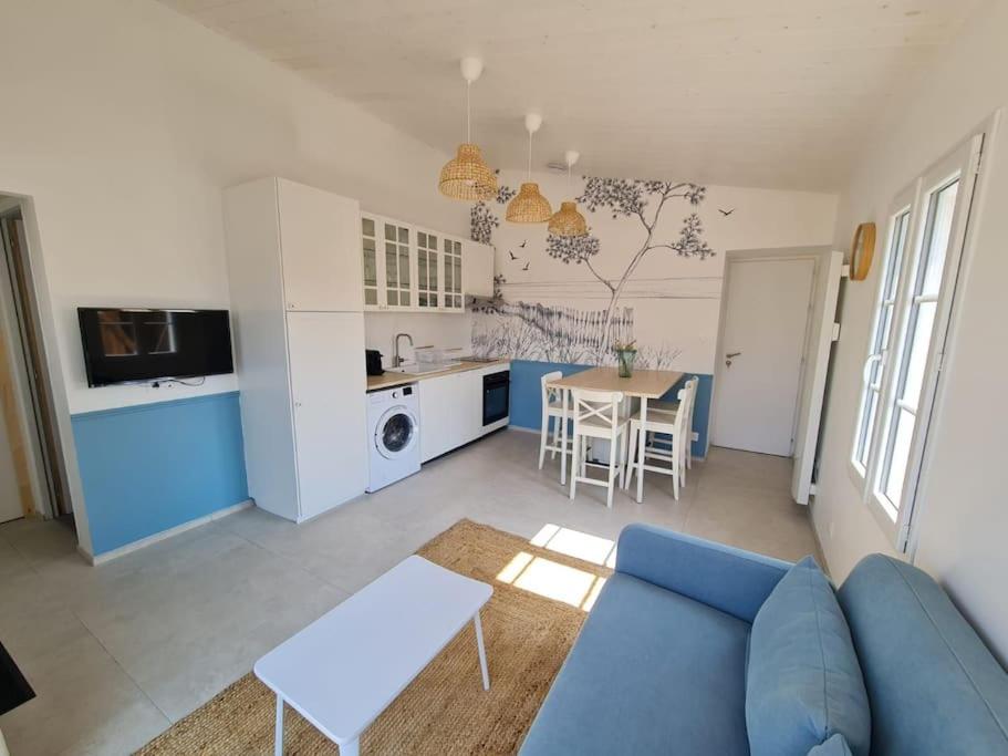 un salon avec un canapé bleu et une cuisine dans l'établissement Maison 4 personnes La nouvelle vague, à La Guérinière