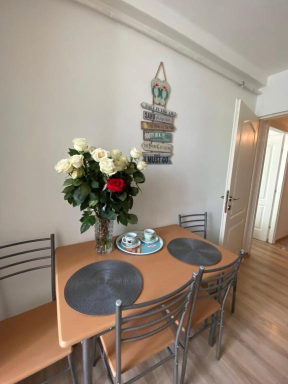 una mesa de comedor con sillas y un jarrón de flores en Cozy Neversea Apartament, en Constanţa