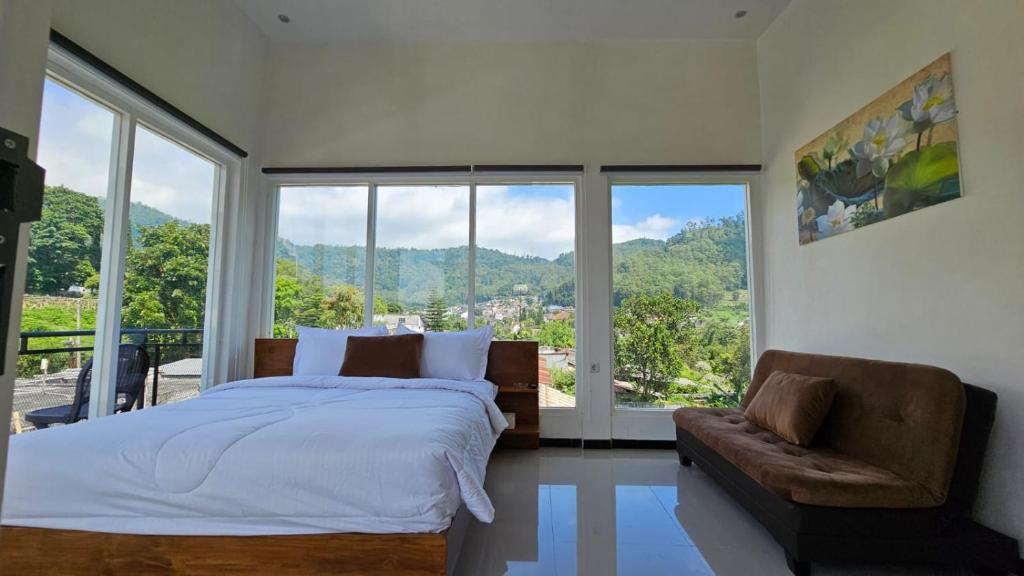 een slaapkamer met een bed, een bank en ramen bij Cahaya 1 Guest House in Songgoriti