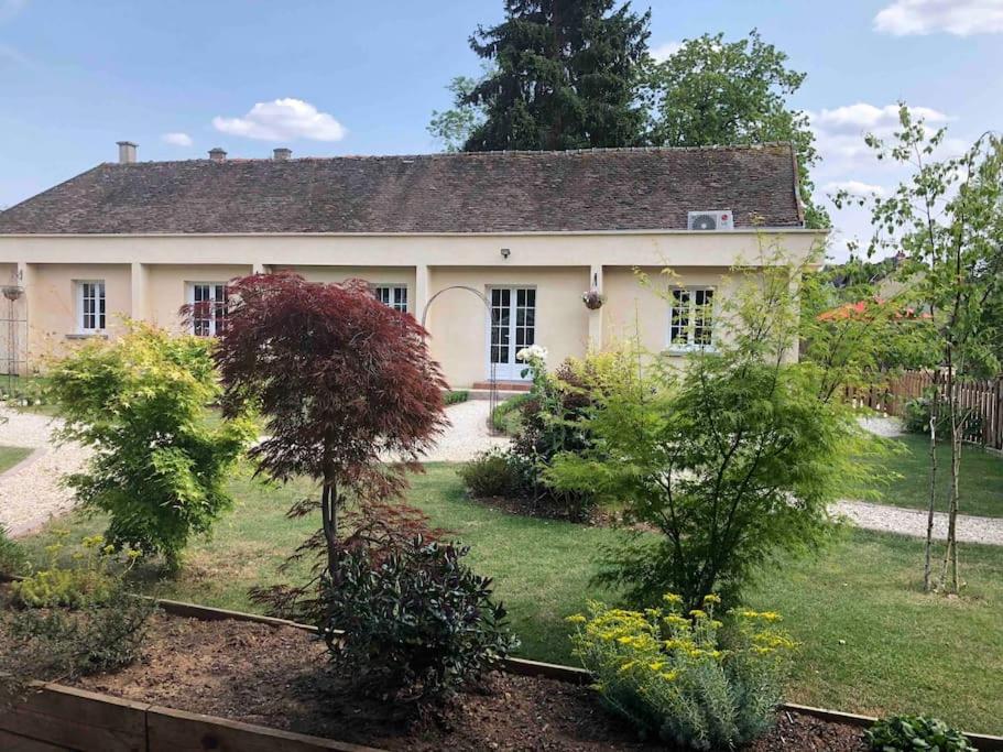 une maison blanche avec des arbres et des buissons devant elle dans l'établissement Riverside Lodge, à Chablis